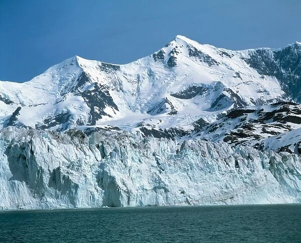 Glacier with mountains behind. A glacier is a body of ice that forms when