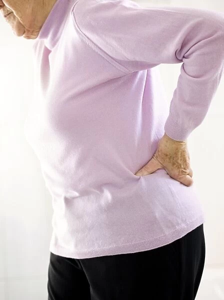 Back pain. MODEL RELEASED. Back pain. Elderly woman holding her painful back