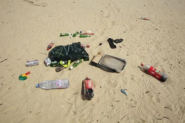 Plastic and glass bottles, plastic bag, disposable barbeque and bong, litter on sandy beach, Studland, Dorset, England