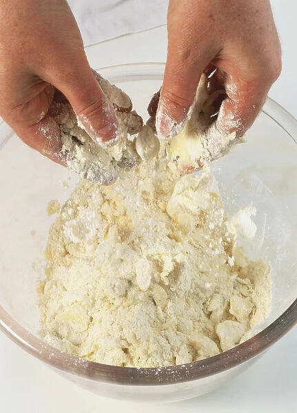 Pair of hands rubbing fat and flour together in a glass bowl, close up