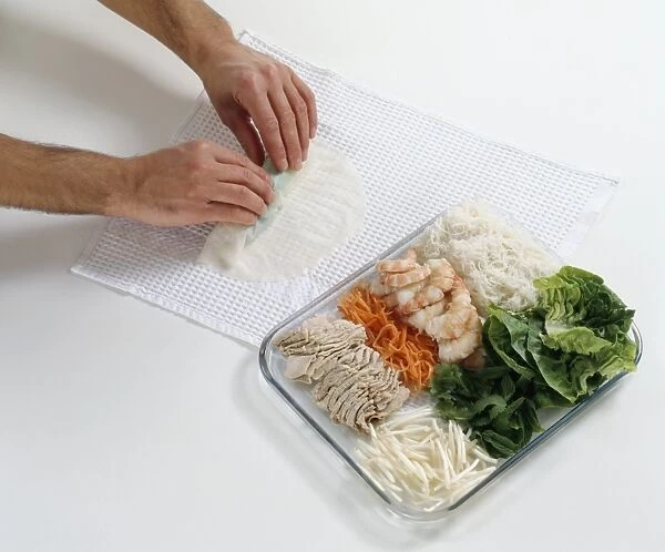 Rolling wet rice paper over ingredients for Vietnamese spring rolls