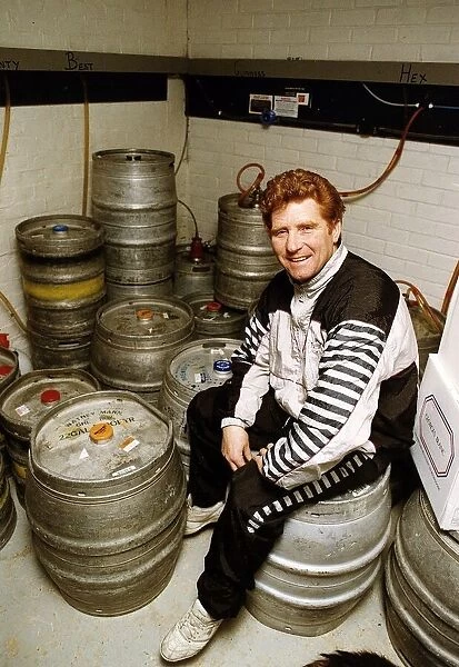 Football player and manager Alan Ball sitting on a barrell in the cellar of his new pub