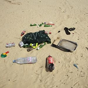 Plastic and glass bottles, plastic bag, disposable barbeque and bong, litter on sandy beach, Studland, Dorset, England