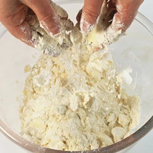Pair of hands rubbing fat and flour together in a glass bowl, close up