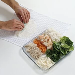 Rolling wet rice paper over ingredients for Vietnamese spring rolls