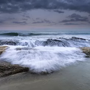 Wave jumping rocks in storms at sea at dawn