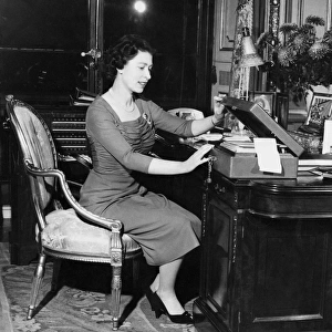HM Queen Elizabeth II at her desk in Buckingham Palace as she opens one of the boxes