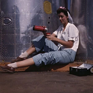 Girl worker at lunch also absorbing Calif... Douglas Aircraft Company, Long Beach, Calif. 1942. Creator: Alfred T Palmer