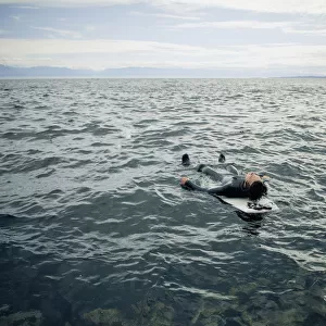 A Surfer Lays On His Back On His Surfboard In The Water; Victoria, British Columbia, Canada