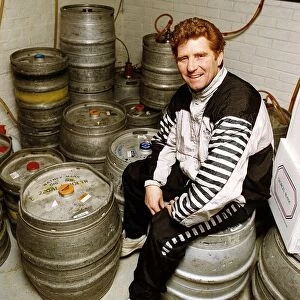 Football player and manager Alan Ball sitting on a barrell in the cellar of his new pub