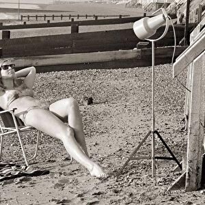 A model sunbathing under a UV lamp on the beach at Cleethorpes November 1967